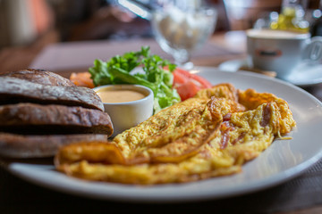 Fresh omelette served with green salad, tomatoes. sause and breab - close up view. Cup of coffee on a background. Traditional breakfast. Healthy food.