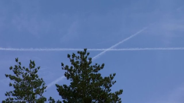 Der Wind verschiebt zwei sich kreuzende Kondensstreifen am tiefblauem Himmel