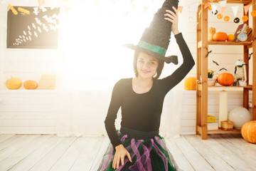 Young beautiful woman in witch costume ready for Halloween celebration in Halloween room decoration.