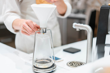 process of preparation black coffee in chemex pour over coffee maker in bright modern cafe. Alternative ways of brewing coffee.