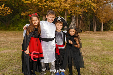 Adorable kids in Halloween costumes hugging in field