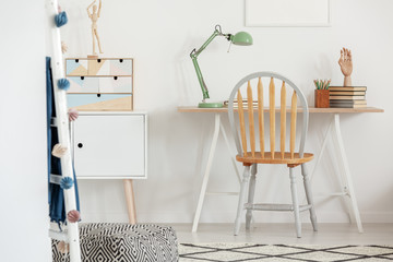 Industrial mint colored lamp on stylish wooden desk in white kid's bedroom