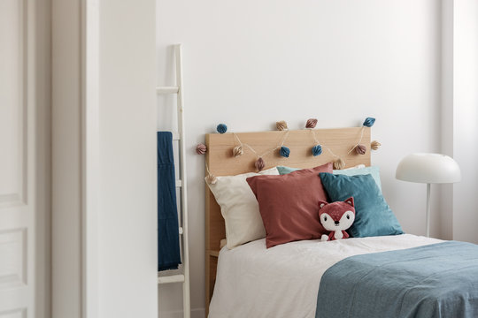 Toy Fox And Blue And Ginger Pillows On Single Bed In White Bedroom Interior For Kid