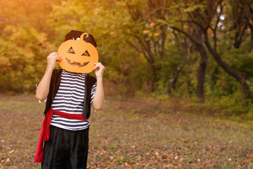 Little boy in Halloween costume standing in autumn forest