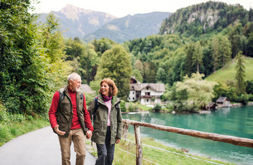 A senior pensioner couple hiking in nature, holding hands.