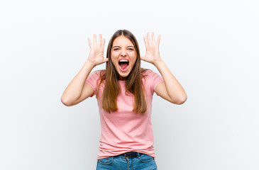 young pretty woman screaming in panic or anger, shocked, terrified or furious, with hands next to...