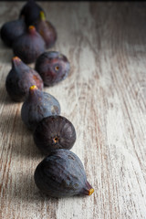 Top view on purple figs with bokeh effect in the background on light wood in vertical