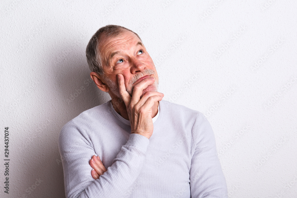 Wall mural Portrait of a thoughtful senior man with beard and mustache in a studio.