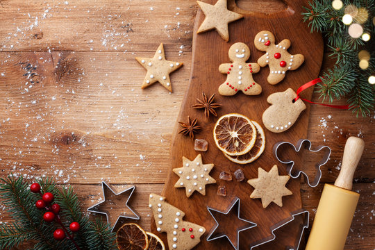 Christmas gingerbread cookies and fir tree on kitchen board top view. Homemade sweet pastries for winter holidays.