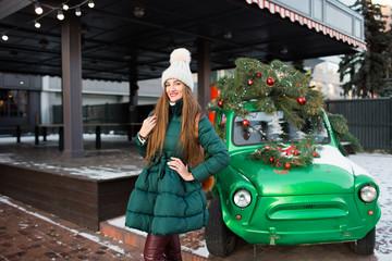Beautiful woman with New Year decorations and balls on background of green retro car.Christmas and New Year holidays.