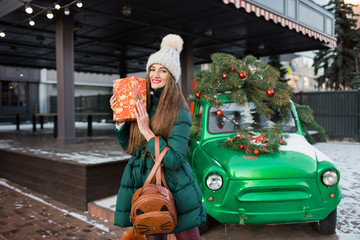 Beautiful woman with New Year decorations and balls on background of green retro car.Christmas and New Year holidays.