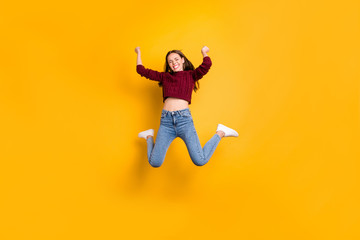 Fototapeta na wymiar Full length photo of delighted woman with her closed eyes and long haircut raising fists wearing burgundy sweater isolated over yellow background