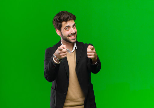young businessman feeling happy and confident, pointing to camera with both hands and laughing, choosing you against green background - Powered by Adobe