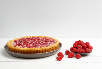 Homemade raspberry pie with yogurt filling on white wooden table. Angle view. Copyspace.