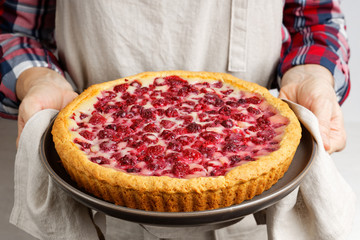Closeup freshly baked homemade raspberry pie with yogurt filling in the hands of the housewife