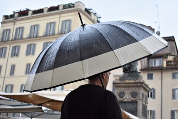 Rear view of an umbrella holded by a man who walks in the rain