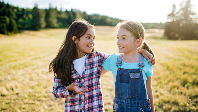 Two school children walking on field trip in nature, talking.