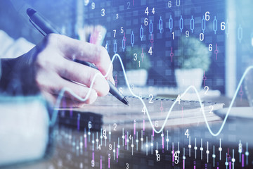 Financial forex charts displayed on woman's hand taking notes background. Concept of research....