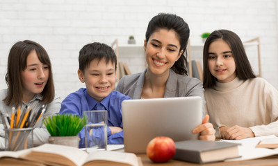 Young teacher showing children tutorials online on tablet