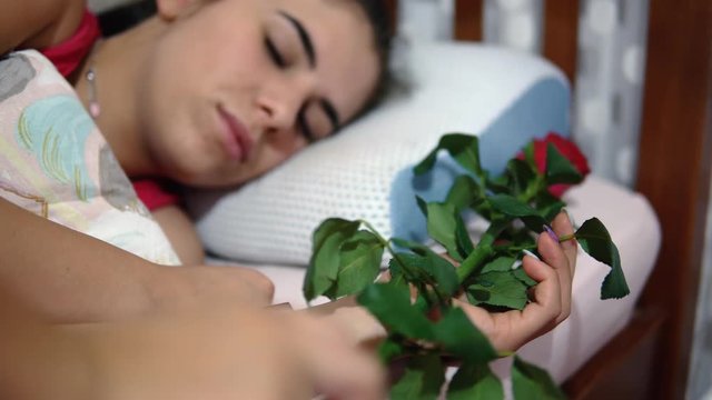 Sleeping girl getting a rose and smiling, romantic gesture