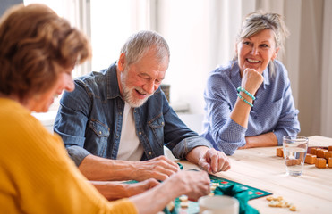 Group of senior people playing board games in community center club. - obrazy, fototapety, plakaty
