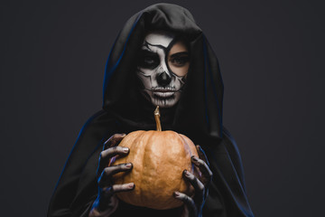 Fototapeta na wymiar Spooky woman with pumpkin celebrating Halloween