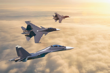 Group of three aircraft fighter jet airplane sun glow flying high in the sky above the clouds.