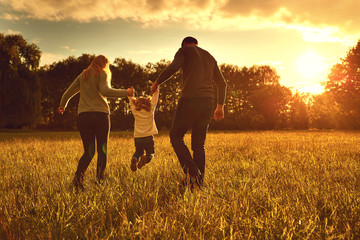 Happy family walks on the park at sunset.