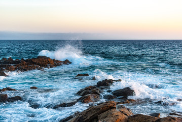 waves crash on stones canary islands, evening ocean