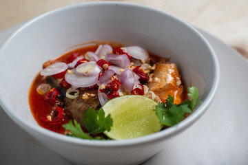 Salad with sardines in tomato sauce in a white side cup