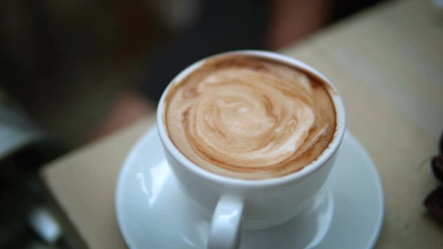 Close up view of a coffee in a white cup on the table in a coffee shop