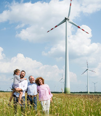 Multigeneration family standing on field on wind farm.