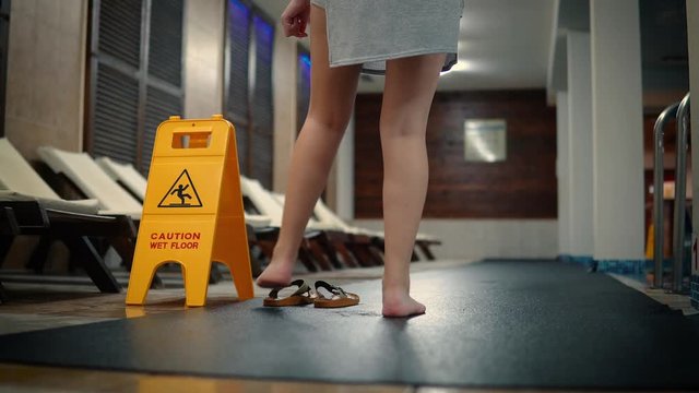CAUTION wet floor sign in empty pool and woman putting her shoes on