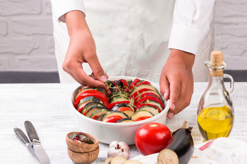 Young female chef prepares ratatouille. Traditional french dish - ratatouille.