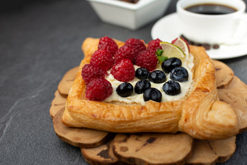 Delicious puff pastries with berries. Fruit cake on wooden board.
