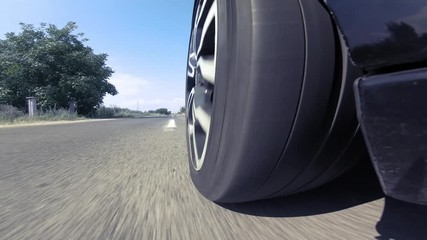 Close up view of car’s wheel spining fast while driving on a highway