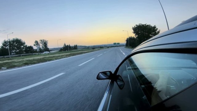 Side rear view mirror on a modern car driving on a highway at sunset