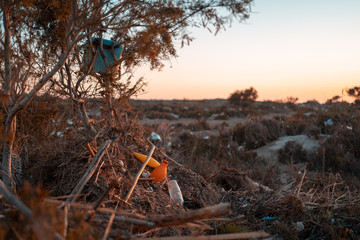 Garbage pile in nature among plants. Toxic plastic into nature everywhere. Rubbish heap in park among vegetation. Contaminated soil. Eco issue.