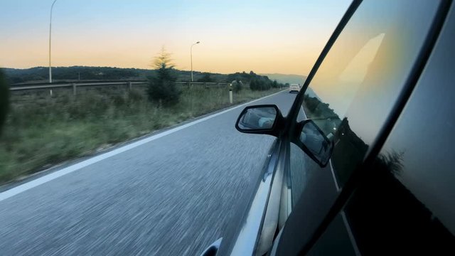 View of the rear view mirror on the car while driving at sunset