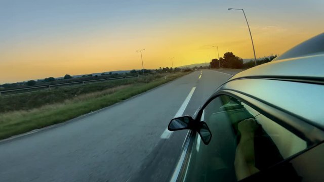 View from the top of the car of rear view mirror while driving on a highway at sunrise