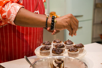 Hands sprinkle on chocolate cupcakes