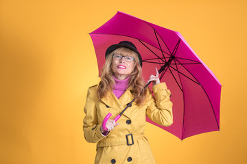 adult woman with umbrella and autumnal clothes isolated on color background