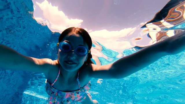 Beautiful girl woth goggles making silly faces and diving towards the camera
