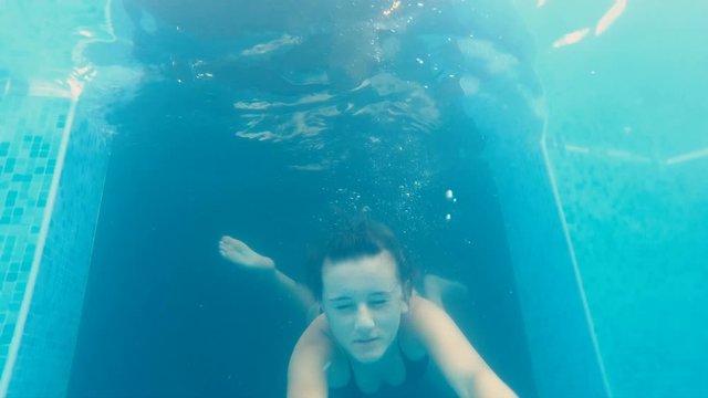 Teen girl swimming underwater in a luxury pool