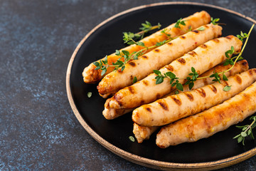 Grilled sausages on black plate with tomato sauce and thyme. Copy space.