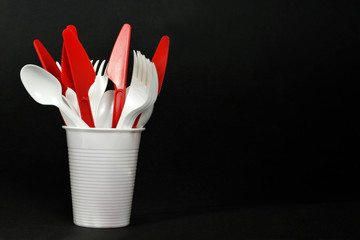 Plastic cutlery. Forks, spoons and knives in disposable plastic cup