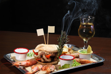 Burger and langoustines with sauce on a tray.