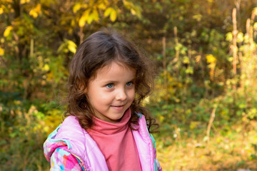 Little girl walks in the autumn forest
