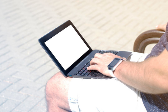 Mockup image blank screen computer with white background for advertising text, hand using laptop contact business search information on desk in office . The man with notebook working in the park.