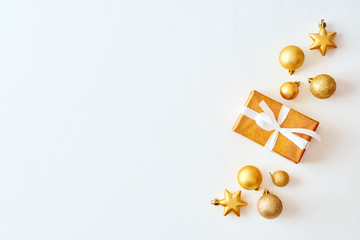 Flat lay christmas border with gold christmas balls and gift box on a white background
